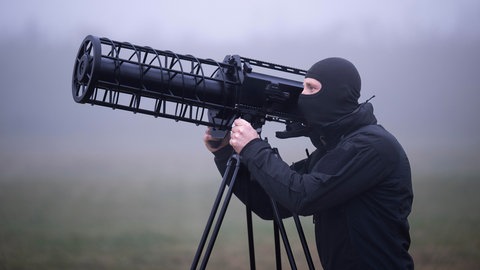 Ein maskierter Beamter nimmt eine anfliegende Drohne mit einem sogenannten Jammer ins Visier