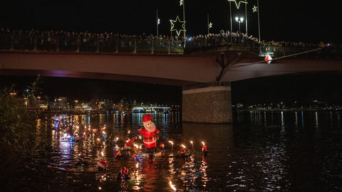 Fackelschwimmer lassen sich am Nikolausabend in der Mosel treiben. Etwa 100 Frauen und Männer sind am Stadtrand von Bernkastel-Kues in den Fluss gestiegen und haben sich zur Altstadt treiben lassen, wo sie unter dem Applaus zahlreicher Zuschauer aus dem Wasser stiegen.