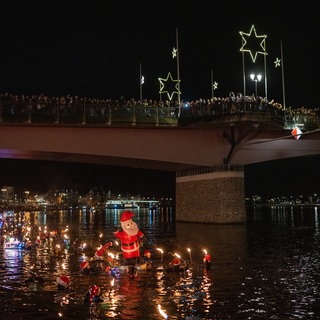 Fackelschwimmer lassen sich am Nikolausabend in der Mosel treiben. Etwa 100 Frauen und Männer sind am Stadtrand von Bernkastel-Kues in den Fluss gestiegen und haben sich zur Altstadt treiben lassen, wo sie unter dem Applaus zahlreicher Zuschauer aus dem Wasser stiegen.