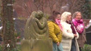 Drei Frauen laufen über einen Friedhof