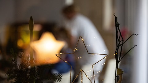 (Symbolbild) Blick durch eine Scheibe auf Weihnachtsdekoration und Pflegerin.