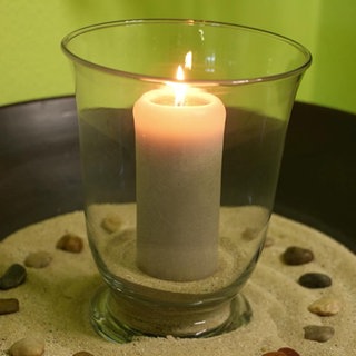 Eine brennende Kerze steht auf einem Tisch
