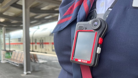 Eine Bahnmitarbeiterin trägt eine Bodycam: Das Land RLP will mehr Sicherheit für Zugbegleiter