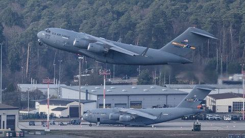 Eine Boeing C-17 Globemaster III der U.S. Air Force startet von der US-Airbase Ramstein, während weitere Militärtransportflugzeuge auf dem Vorfeld stehen.