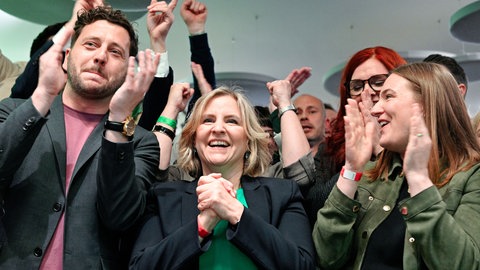 Katrin Eder (M), rheinland-pfälzische Ministerin für Klimaschutz, Umwelt, Energie und Mobilität und Spitzenkandidatin von Bündnis 90Die Grünen für die Landtagswahl in Rheinland-Pfalz, und Felix Banaszak (l), Bundesvorsitzender von Bündnis 90Die Grünen, reagieren auf die erste Hochrechnung bei der Wahlparty von Bündnis 90Die Grünen.