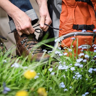 Eine Wandererin schnürt ihre Wanderschuhe. Diese Ausflüge an Ostern lohnen sich jetzt