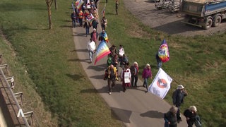 Viele Menschen laufen mit Fahnen beim Ostermarsch in Büchel