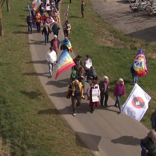 Viele Menschen laufen mit Fahnen beim Ostermarsch in Büchel