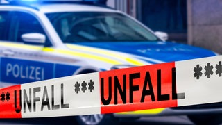 Polizefahrzeug mit Blaulicht hinter einem Absperrband (Sujetbild)