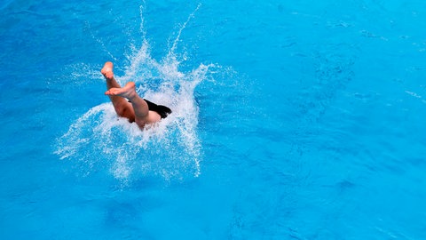 Ein Mann springt ins Becken eines Schwimmbades - im April öffnen die ersten Freibäder in Rheinland-Pfalz (Symbolbild).