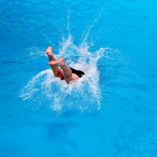 Ein Mann springt ins Becken eines Schwimmbades - im April öffnen die ersten Freibäder in Rheinland-Pfalz (Symbolbild).
