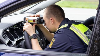 Ein Polizist kontrolliert die Geschwindigkeit von Autos. In Rheinland-Pfalz geht die Polizei eine Woche lang mit einem Blitzermarathon verstärkt gegen Raser vor.