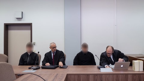 Die beiden Angeklagten sitzen im Landgericht zwischen ihren Anwälten. 