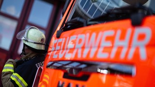 Feuerwehrmann neben Feuerwehrauto. In Irrel in der Eifel hat ein Wohnhaus gebrannt. 