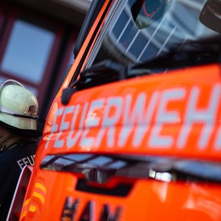 Feuerwehrmann neben Feuerwehrauto. In Irrel in der Eifel hat ein Wohnhaus gebrannt. 