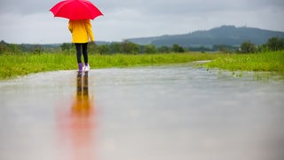 Eine Spaziergängerin in Gummistiefeln. In RLP wird es diese Woche nass und regnerisch.