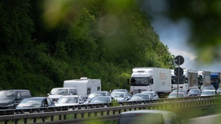 Autos stehen auf einer Autobahn hinter einer Leitplanke im Stau an einem Pfingstwochenende.