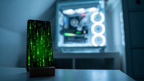 Handy mit Matrix vor einem Server (Symbolbild): In RLP wurden Fotos von Schul- und Kitakidnern und deren Daten gestohlen.
