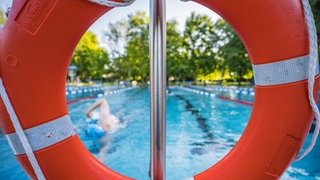 Ein Schwimmer zieht in einem Freibad seine Bahnen.