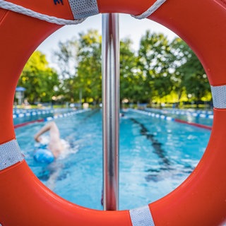 Ein Schwimmer zieht in einem Freibad seine Bahnen.