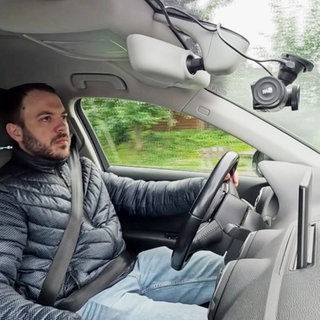 Ein Autofahrer mit einer Dashcam an der Windschutzscheibe. 