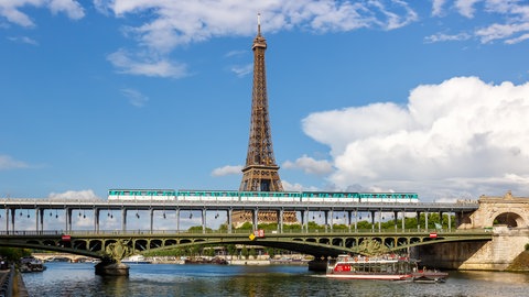 Die Metro fährt über der Seine, im Hintergrund der Eiffelturm - mit dem Deutschlandticket können junge Menschen im Sommer umsonst nach Frankreich fahren.