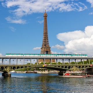 Die Metro fährt über der Seine, im Hintergrund der Eiffelturm - mit dem Deutschlandticket können junge Menschen im Sommer umsonst nach Frankreich fahren.