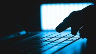 Hand auf einer Laptop Tastatur in einem dunklen Raum (Symbol) - Minderjähriger aus RLP wegen IS-Aktivitäten verurteilt