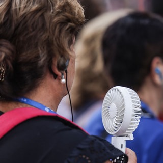 Weiter heiß: Eine Frau hält sich bei heißem Sommerwetter einen Handventilator vor das Gesicht.