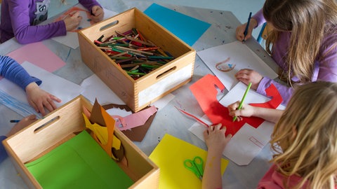Grundschülerinnen sind in einem Kinderhort mit Bastelarbeiten beschäftigt. Nach den Sommerferien haben alle Erstklässler in RLP einen Anspruch auf Ganztagsbetreuung.