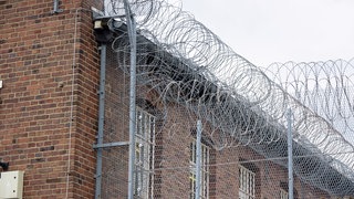 Eine Justizvollzugsanstalt mit Stacheldraht und vergitterten Fenstern.
