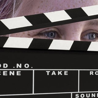 Eine Frau schaut durch eine Filmklappe