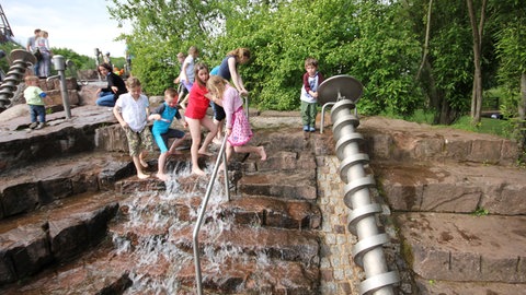 Kinder spielen auf dem Wasserspielplatz auf der Gartenschau in Kaiserslautern.