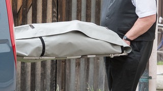 Bestatter mit Leichenwagen und Leiche