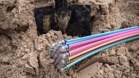Glasfaserkabel liegen im Sand, bevor sie verlegt werden (Symbolfoto).