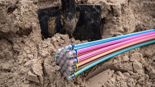 Glasfaserkabel liegen im Sand, bevor sie verlegt werden (Symbolfoto).