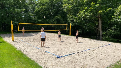Junge Badegäste spielen Volleyball im Warmfreibad Trippstadt.