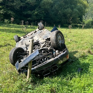 Nach einem Unfall durch einen Fahranfänger bei Altenglan (Kreis Kusel) zerstörtes Auto in einer Wiese auf dem Dach liegend