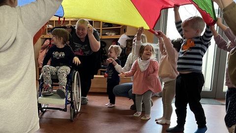 Marlene (5) sitzt im Rollstuhl und besucht die Integrative Kita "Stadtindianer" der Lebenshilfe in Kaiserslautern. Hier gehört die Therapie – noch – zum Kita-Alltag.