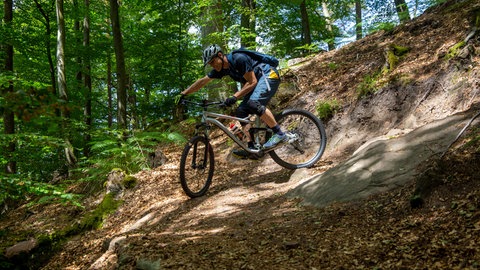 Ein Mountainbiker fährt eine enge Spitzkehre im Mountainbikepark Pfälzerwald bei Dahn. Viele der Touren und Trails sind gut mit der Bahn erreichbar