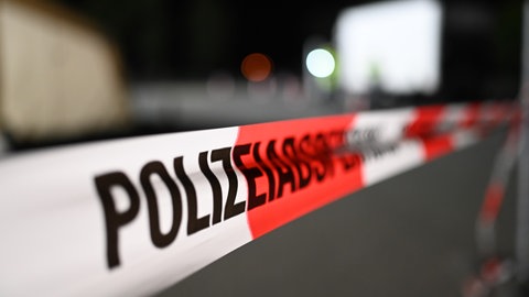 Symbolbild einer Polizeiabsperrung mit Flatterband. In Kaiserslautern ist ein Mann eine Hausfassade hochgeklettert und abgestürzt.