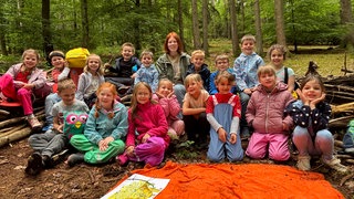 Laura Krauß mit den Schülern der 1c der Grundschule Mackenbach. Im Wald haben die Kinder viel Spaß. 