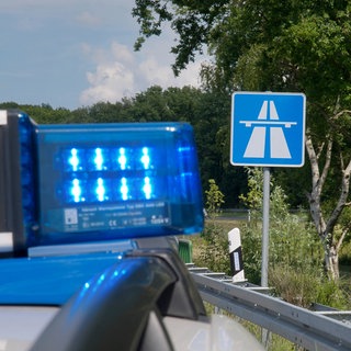 Polizeiauto steht vor Autobahnschild - Polizei stoppt illegales Autorennen auf A63.