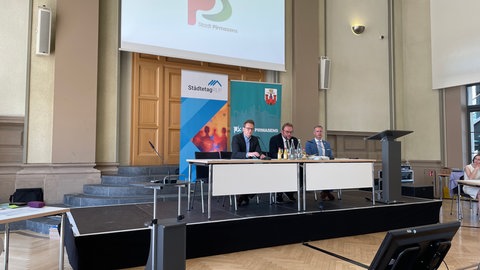 Drei Männer sitzen im Rathaus an einem Tisch - Pirmasens verklagt Land wegen Finanzen