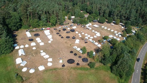 Die Campingplätze in der Pfalz für größere Gruppen wie der Jugendzeltplatz Hauenstein sind trotz des Regens gut ausgelastet. (Das Luftbild aus dem Sommer 2022 zeigt die große Wiesenfläche des Campingplatzes.)