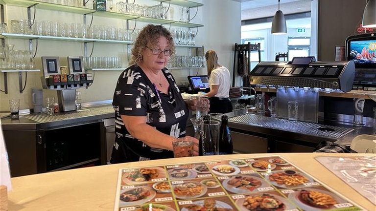 Eine Frau schaut sich gerade das bebilderte Essensangebot auf dem Tisch in der Raststätte am Autohof in Ramstein an.