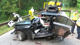 Polizei und Abschleppdienst arbeiten an der Unfallstelle. Bei einem Verkehrsunfall auf einer Landstraße sind ein 21 Jahre alter Autofahrer und seine gleichaltrige Beifahrerin ums Leben gekommen.