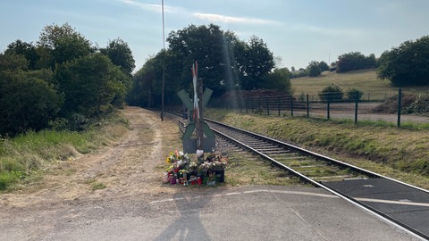 Trauerkerzen und Blumen für die Verstorbene an Andreaskreuzen des Bahnübergangs in Kusel. 