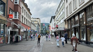 Eine Frau mit Kopftuch läuft in der Fußgängerzone in Kaiserslautern in Richtung der Mall.