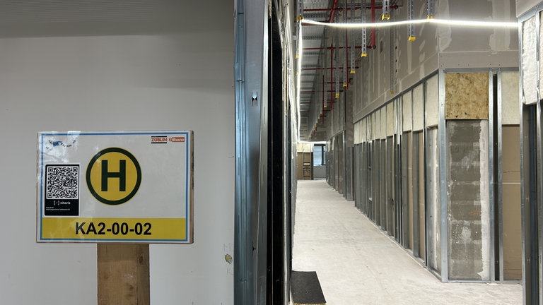 Im Gebäude sind Haltepunkte-Schilder für Materiallieferungen an den Wänden angebracht, da der rießige Bau wie ein Labyrinth wirkt.